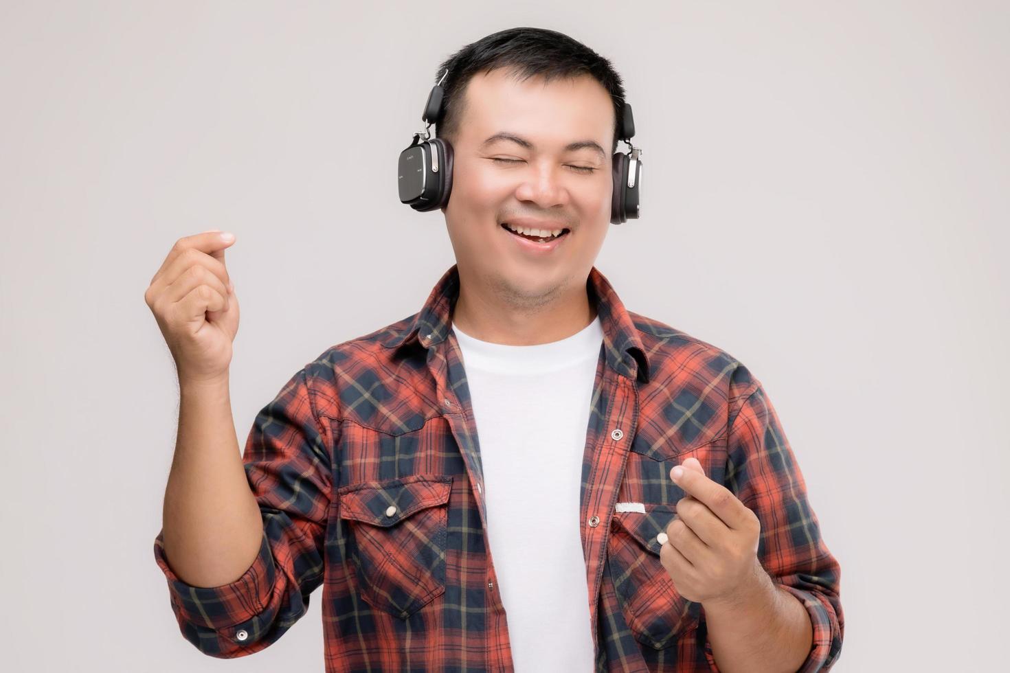 portrait homme asiatique écoutant une chanson ou de la musique à partir d'un casque noir. tourné en studio isolé sur gris photo