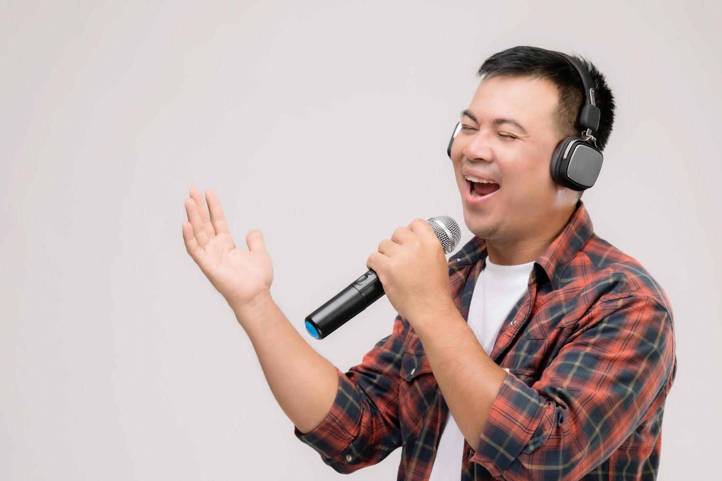 portrait homme asiatique écoutant une chanson ou de la musique à partir d'un casque noir. tourné en studio isolé sur gris photo