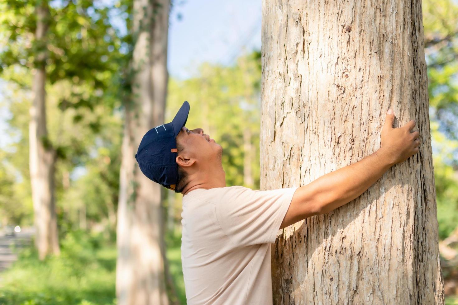 homme asiatique donnant un câlin sur un grand câlin de teck. arbre d'amour et concept de nature ou d'environnement photo