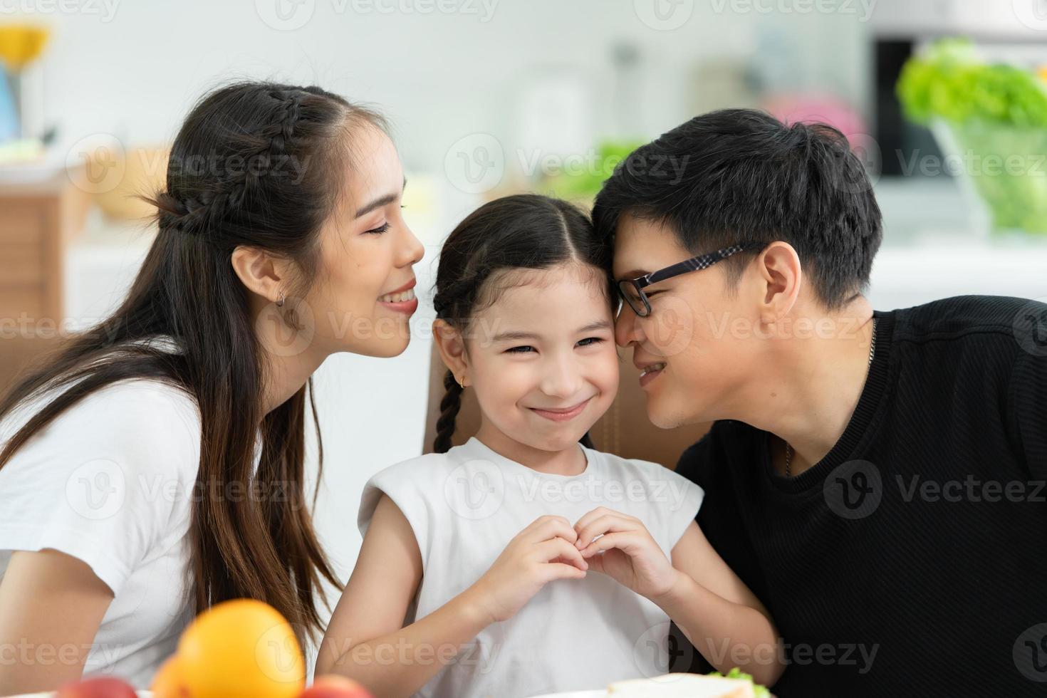 père et mère asiatiques montrent votre amour à la petite fille et prennent le petit déjeuner ensemble joyeusement dans la salle à manger de la maison. photo