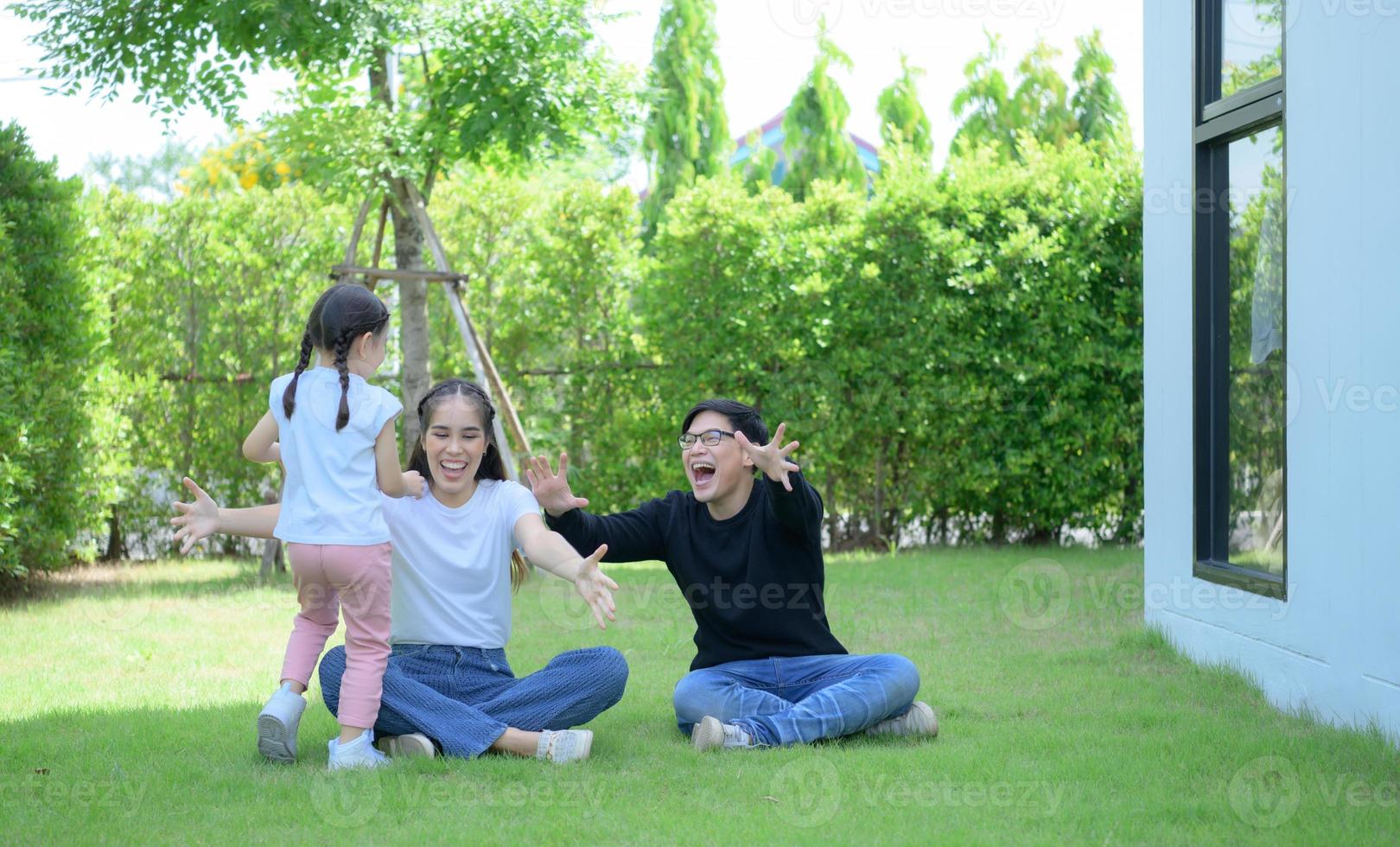 famille asiatique avec père, mère et fille s'amusant joyeusement dans le jardin de la maison photo