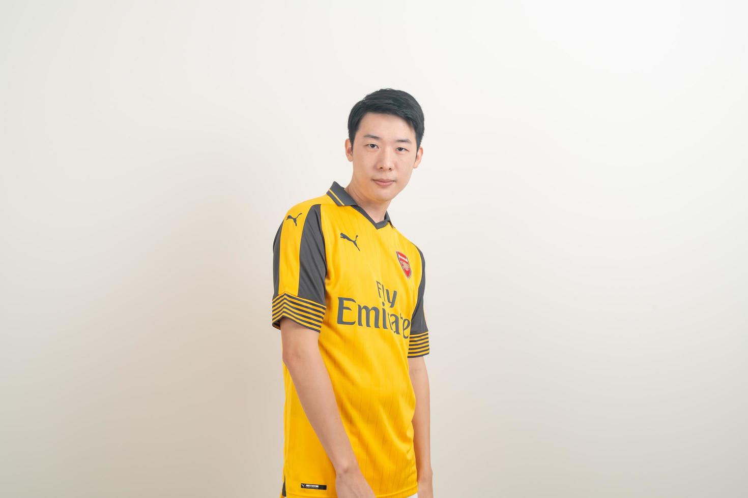 bangkok, thaïlande - 27 novembre 2021 - jeune homme asiatique portant une chemise d'arsenal avec un fond blanc. photo