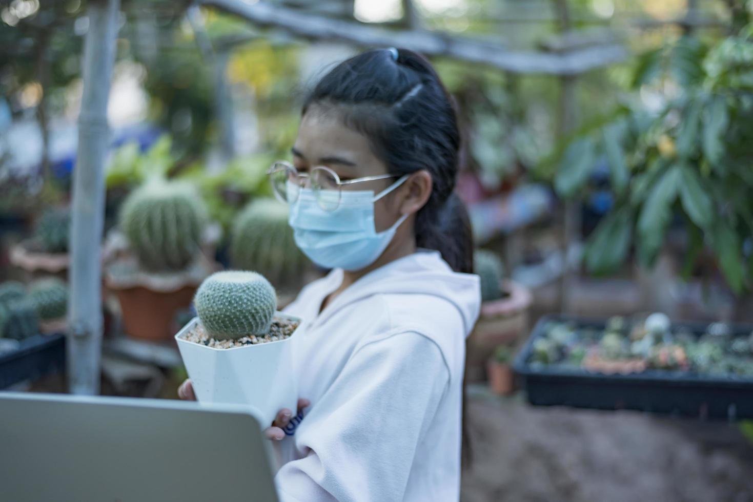 belle fille asiatique ouvrière de serre vendant de petites plantes sur les médias sociaux en direct avec mobile. aménagement paysager de petits arbres et jardinier de décoration de jardin à la maison. photo