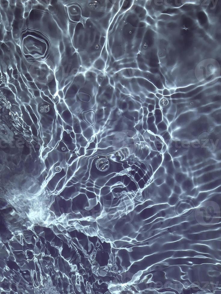défocalisation floue transparente bleu clair texture de surface de l'eau calme avec des éclaboussures et des bulles. fond de nature abstraite à la mode. vagues d'eau au soleil. photo