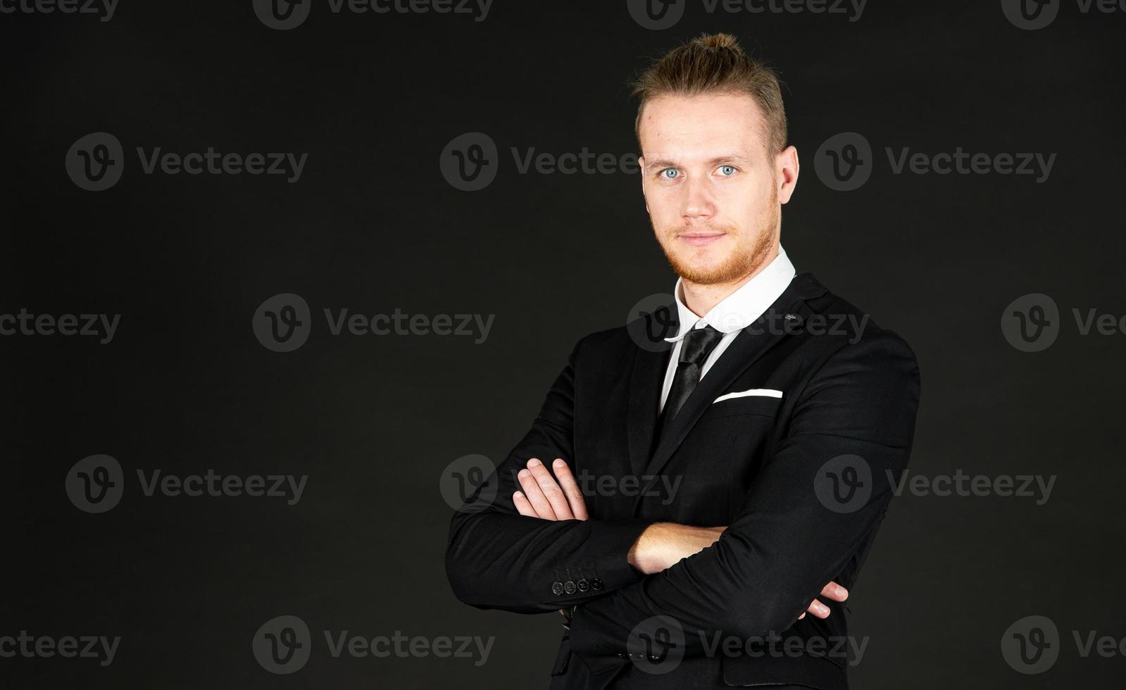 portrait de jeune homme d'affaires intelligent et beau en costume noir debout sur fond noir isolé. photo