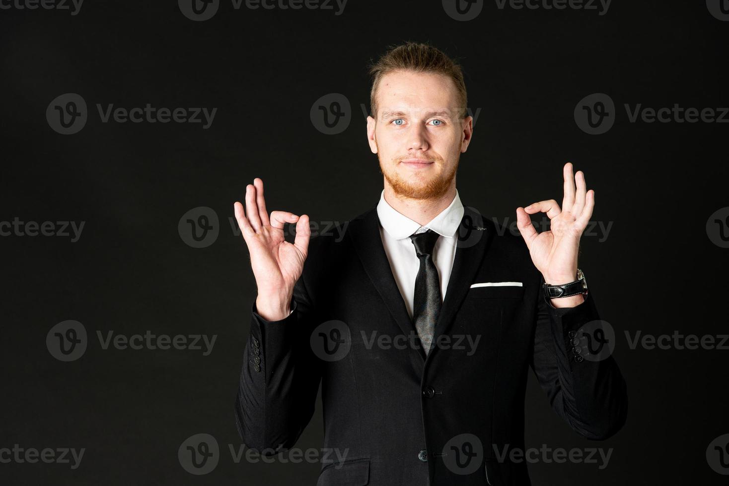 portrait de jeune homme d'affaires intelligent et beau en costume noir debout sur fond noir isolé. photo