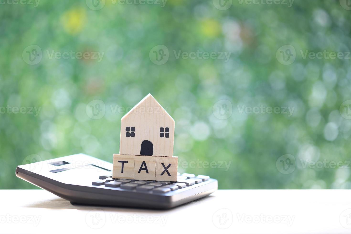 impôt foncier, maison modèle sur calculatrice avec mot fiscal sur fond vert naturel, concept d'investissement commercial et d'impôt foncier photo