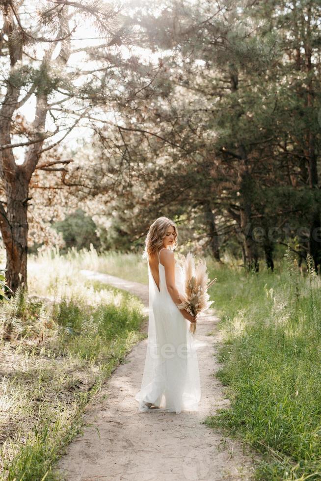 fille mariée heureuse dans une robe légère blanche avec un bouquet de fleurs séchées photo