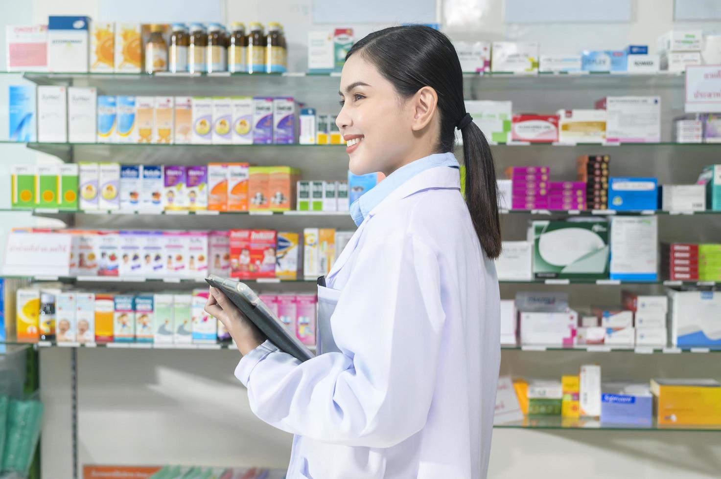 portrait d'une pharmacienne à l'aide d'une tablette dans une pharmacie de pharmacie moderne. photo