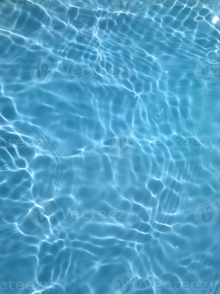 défocalisation de l'eau bleue floue dans la piscine fond de détail de l'eau ridée. surface de l'eau dans la mer, fond de l'océan. l'eau est une substance inorganique, transparente, insipide, inodore et presque incolore. photo