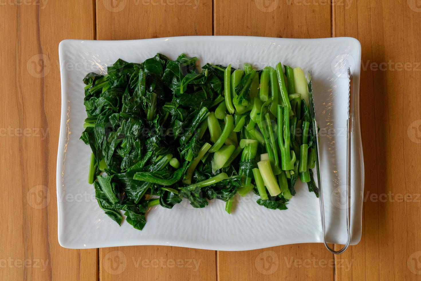 des légumes de chou chinois thaï glissés et bouillis séparés sont posés sur le rectangle blanc de la table en bois. photo