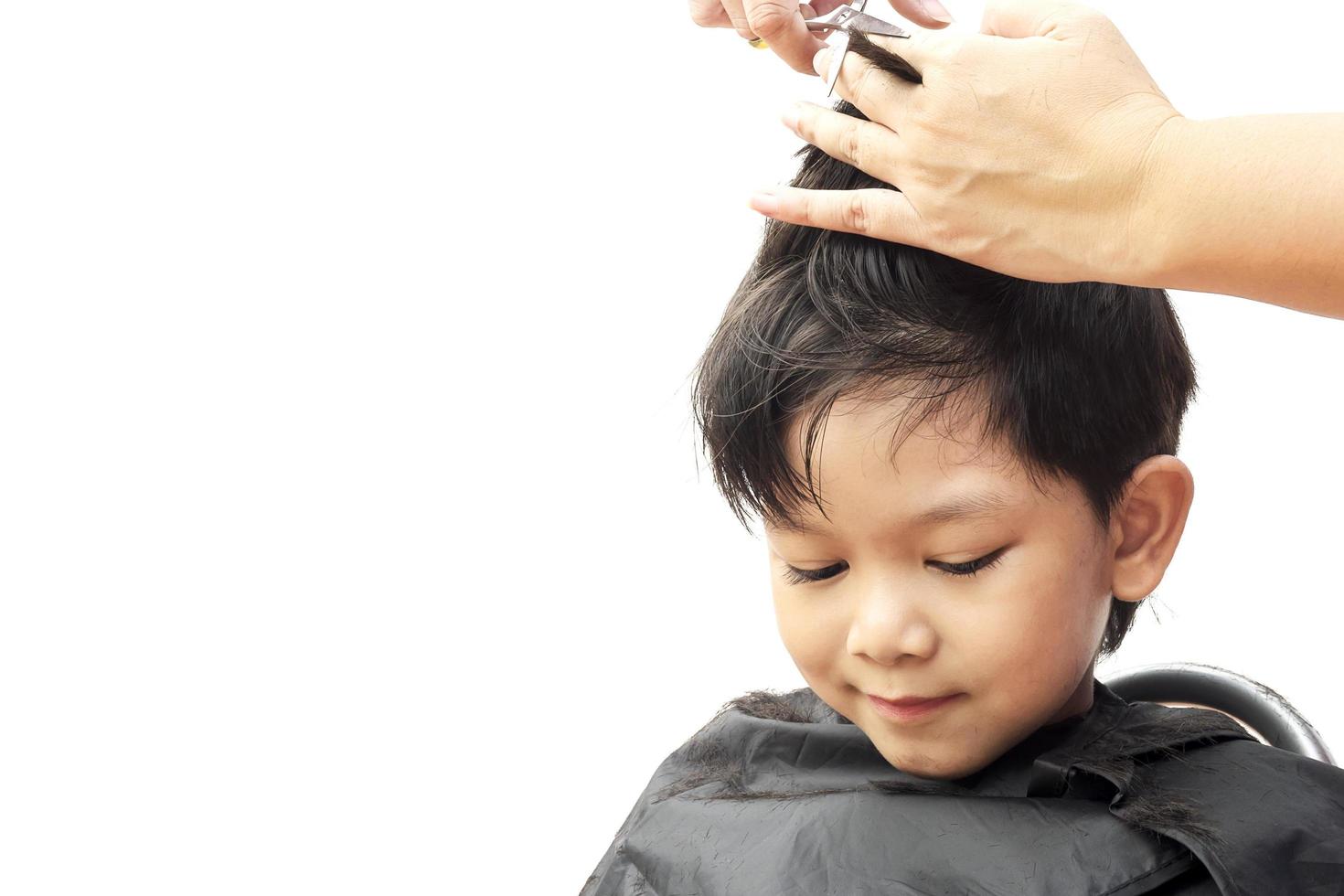 Un garçon est coupé ses cheveux par coiffeur isolé sur fond blanc photo