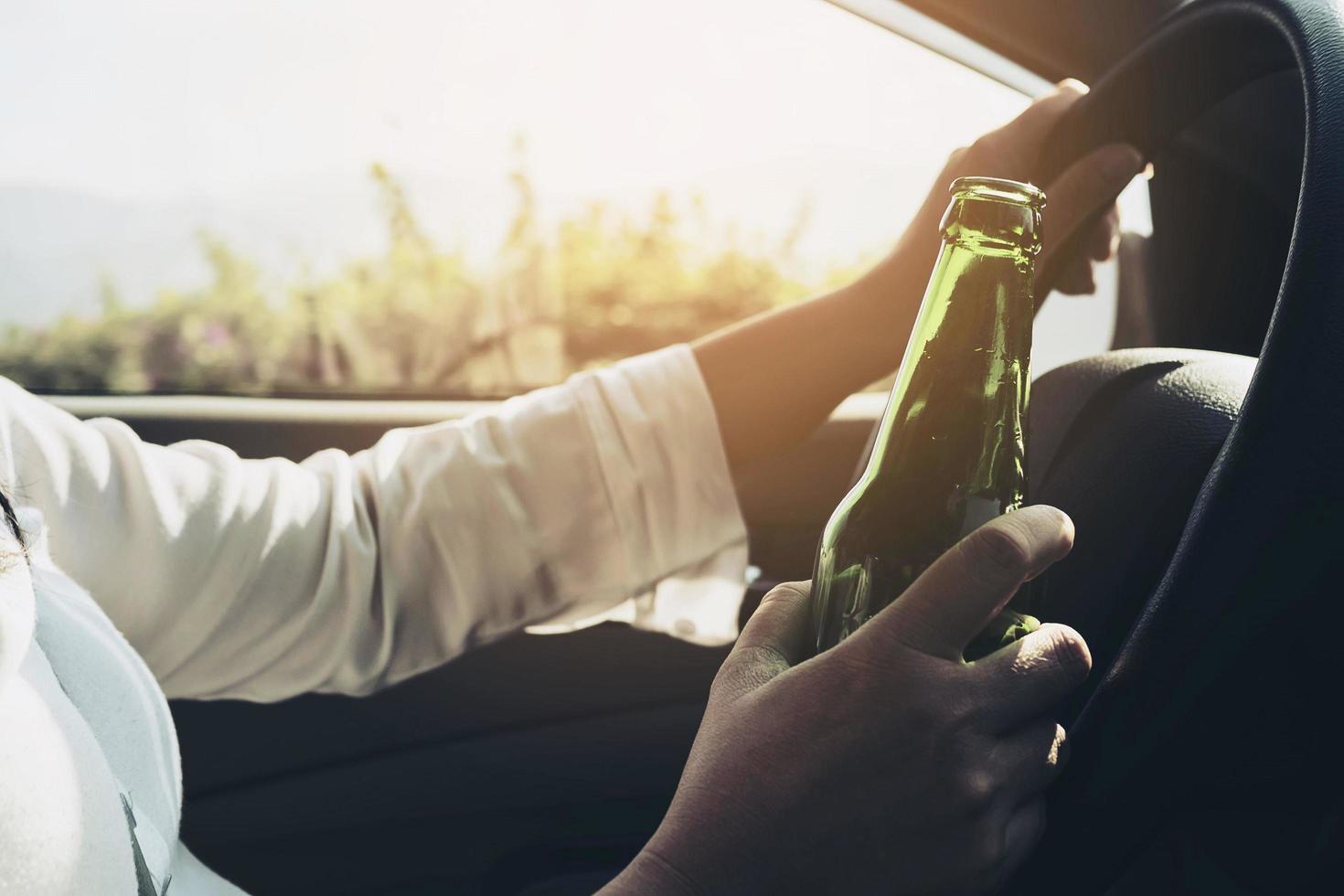 femme tenant une bouteille de bière en conduisant une voiture photo