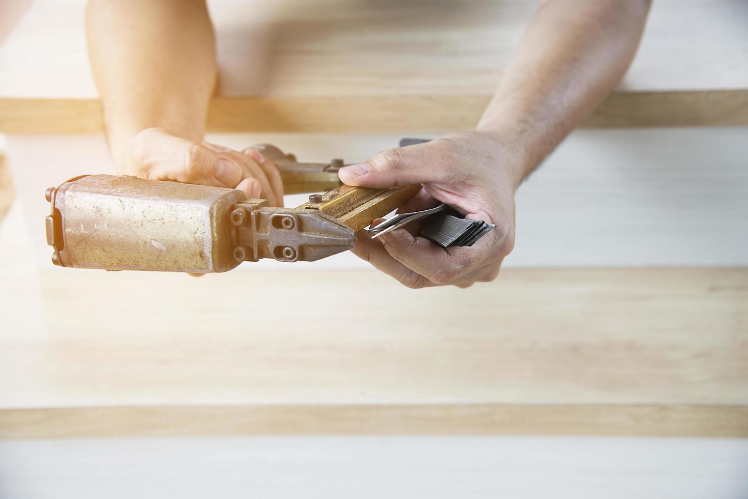 Charpentier à l'aide d'un pistolet à air comprimé faisant des travaux de meubles en bois photo