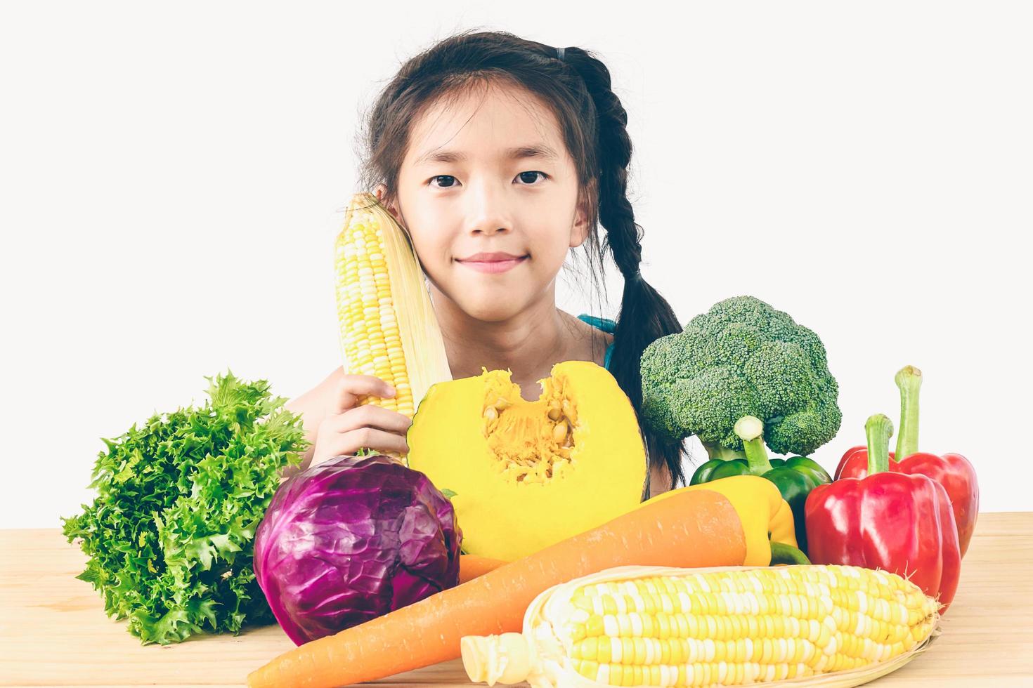 photo de style vintage d'une jolie fille asiatique montrant une expression de plaisir avec des légumes frais colorés isolés sur fond blanc