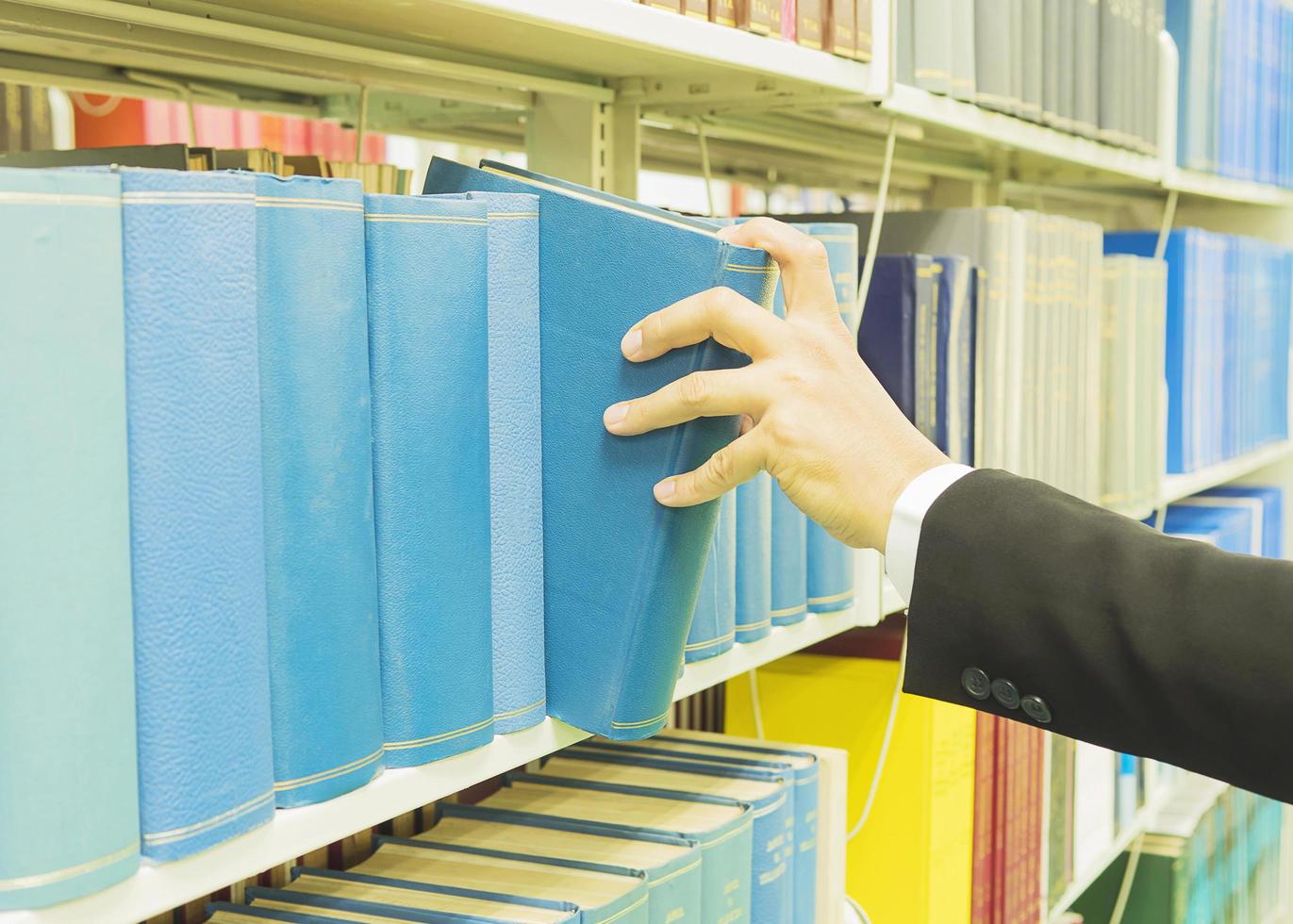 photo vintage d'un homme sélectionne le livre d'une étagère dans une bibliothèque