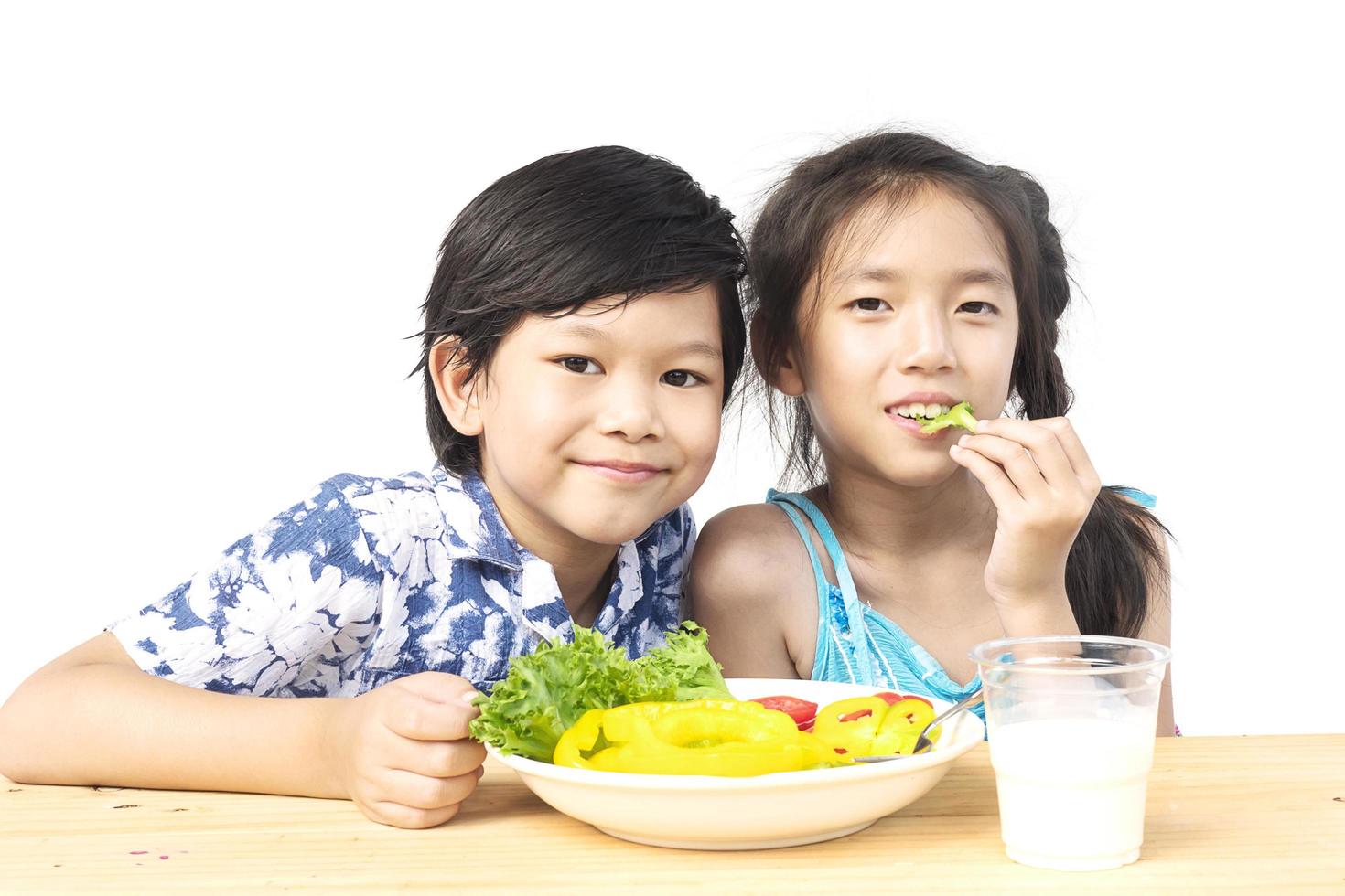 Adorable garçon asiatique montrant profiter de l'expression avec des légumes frais colorés et un verre de lait isolé sur fond blanc photo