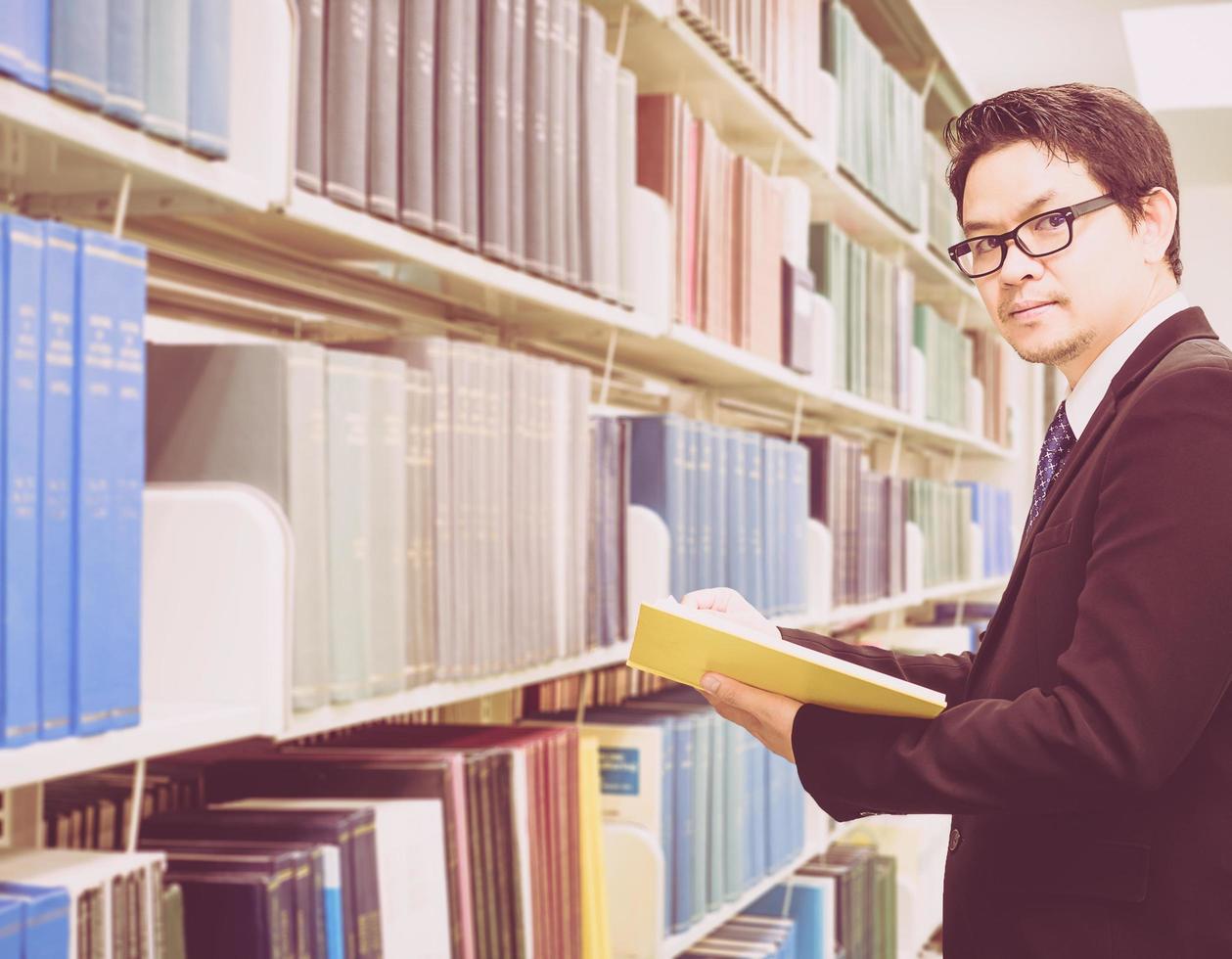 photo vintage d'un homme d'affaires tenant un livre dans une bibliothèque