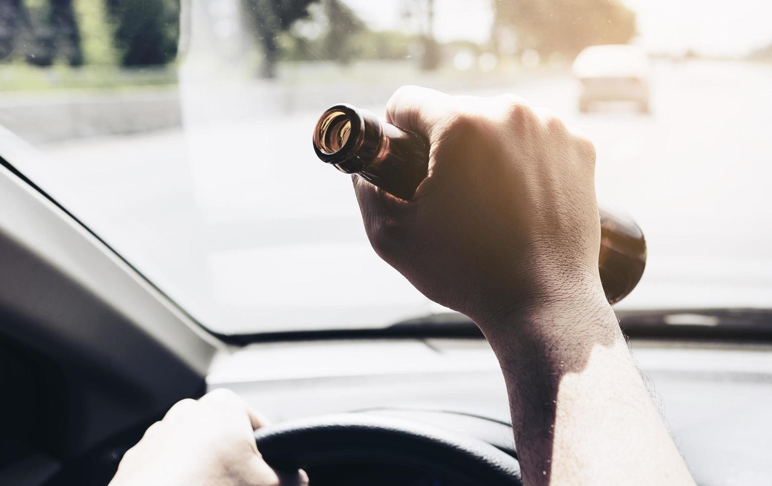 homme tenant une bouteille de bière en conduisant une voiture photo