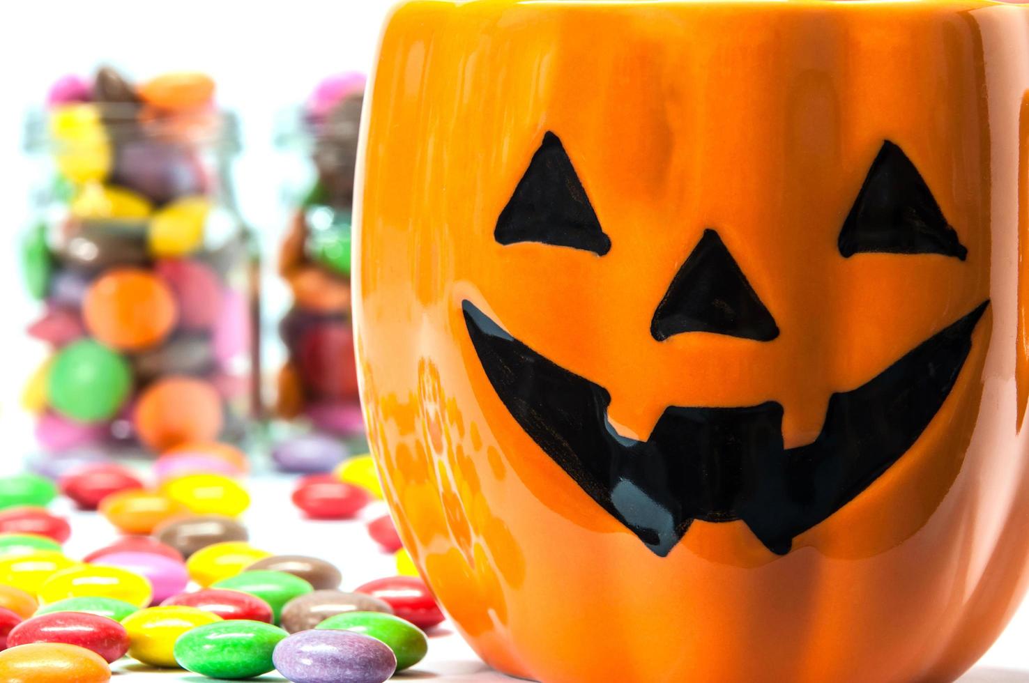 seaux de visage de citrouille d'halloween avec des bonbons colorés photo