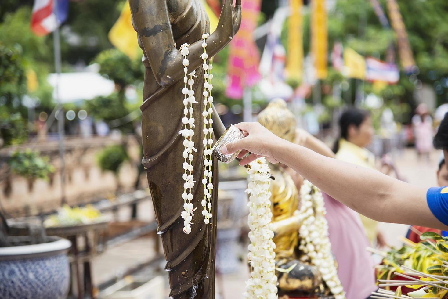 les gens versent de l'eau sur une image de bouddha c'est un geste d'adoration - les gens participent au festival bouddhiste traditionnel annuel de chiang mai. photo