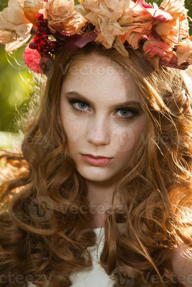 jeune femme tenant un tas de feuilles d'érable jaune. portrait d'automne de jeune femme. fille aux cheveux rouges dans la forêt d'automne photo