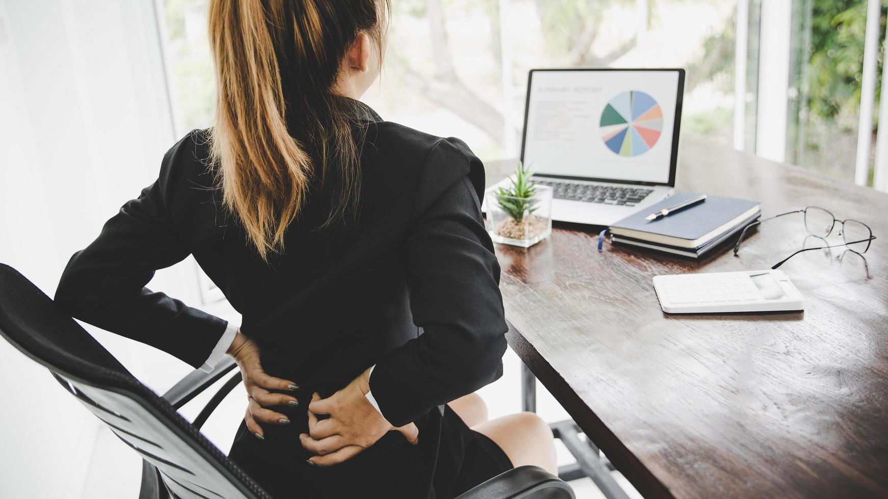 jeune femme d'affaires au bureau avec de terribles maux de dos photo