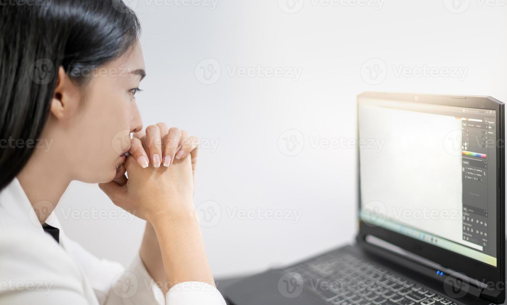 les jeunes asiatiques ressentent le stress du travail, assis devant l'ordinateur portable dans leur maison. photo