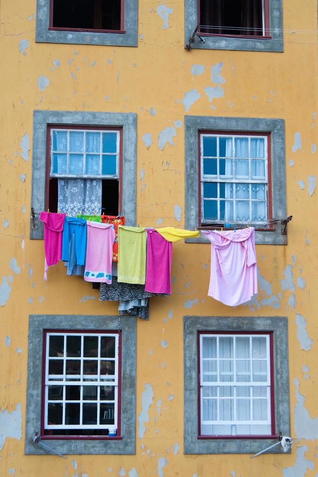 gros plan sur une façade jaune d'un immeuble ancien du centre-ville de porto. vêtements suspendus colorés à sécher photo