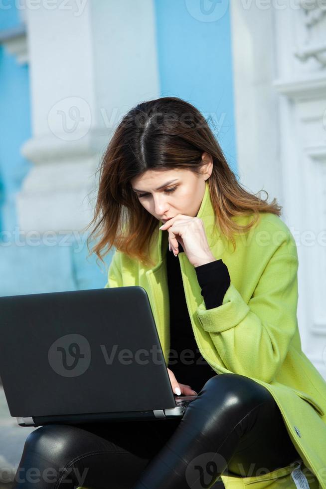 la fille travaille à l'ordinateur dans un café. étudiant apprenant en ligne. blogueur. jeune écrivaine caucasienne tapant sur un ordinateur portable. femme d'affaires attrayante utilisant un ordinateur portable pendant une pause. photo