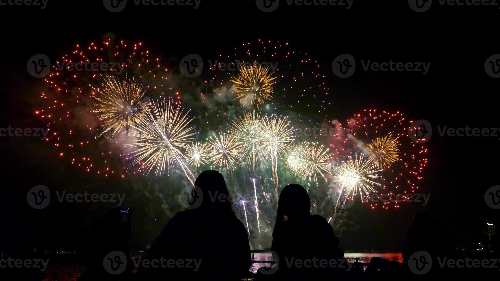 les gens regardent de beaux feux d'artifice ensemble au bord de la mer la nuit. photo