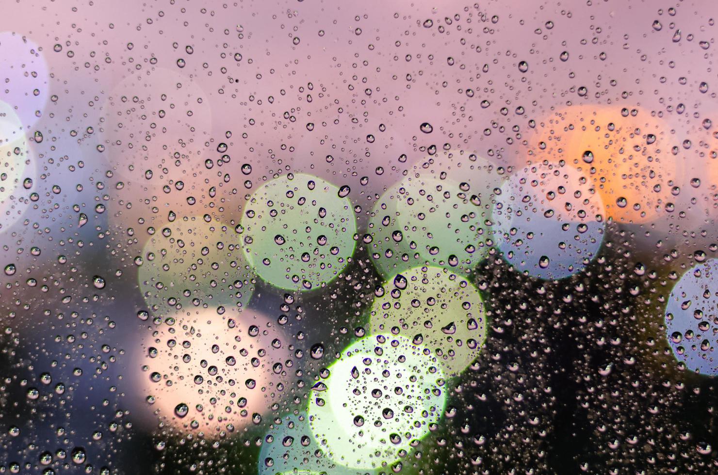 goutte de pluie sur la fenêtre en verre pendant la saison de la mousson avec lumière bokeh colorée photo