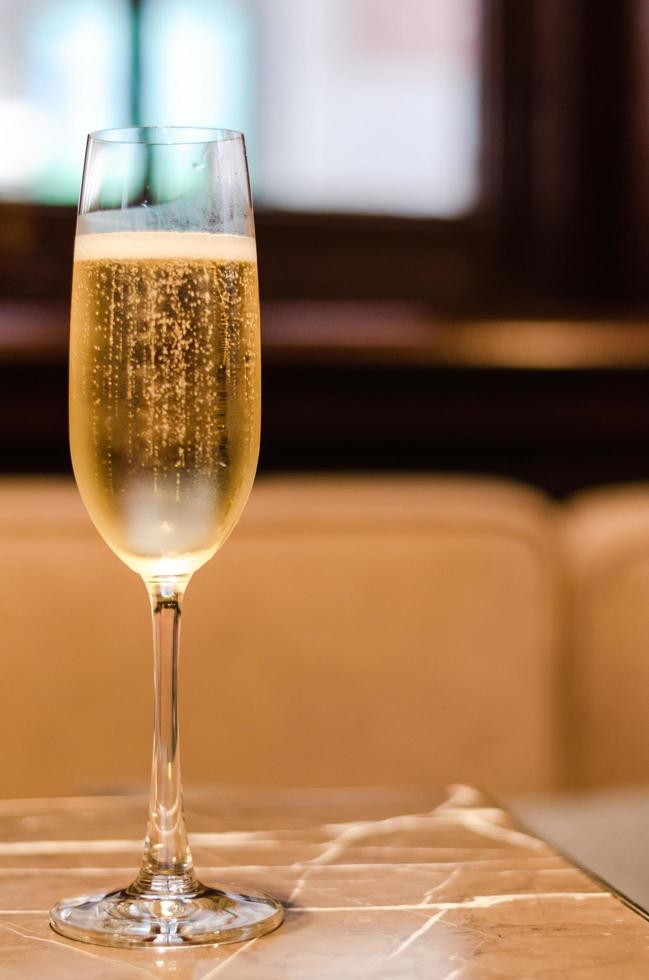 une coupe de champagne met sur une table en marbre au restaurant pour une célébration avec un arrière-plan flou. photo