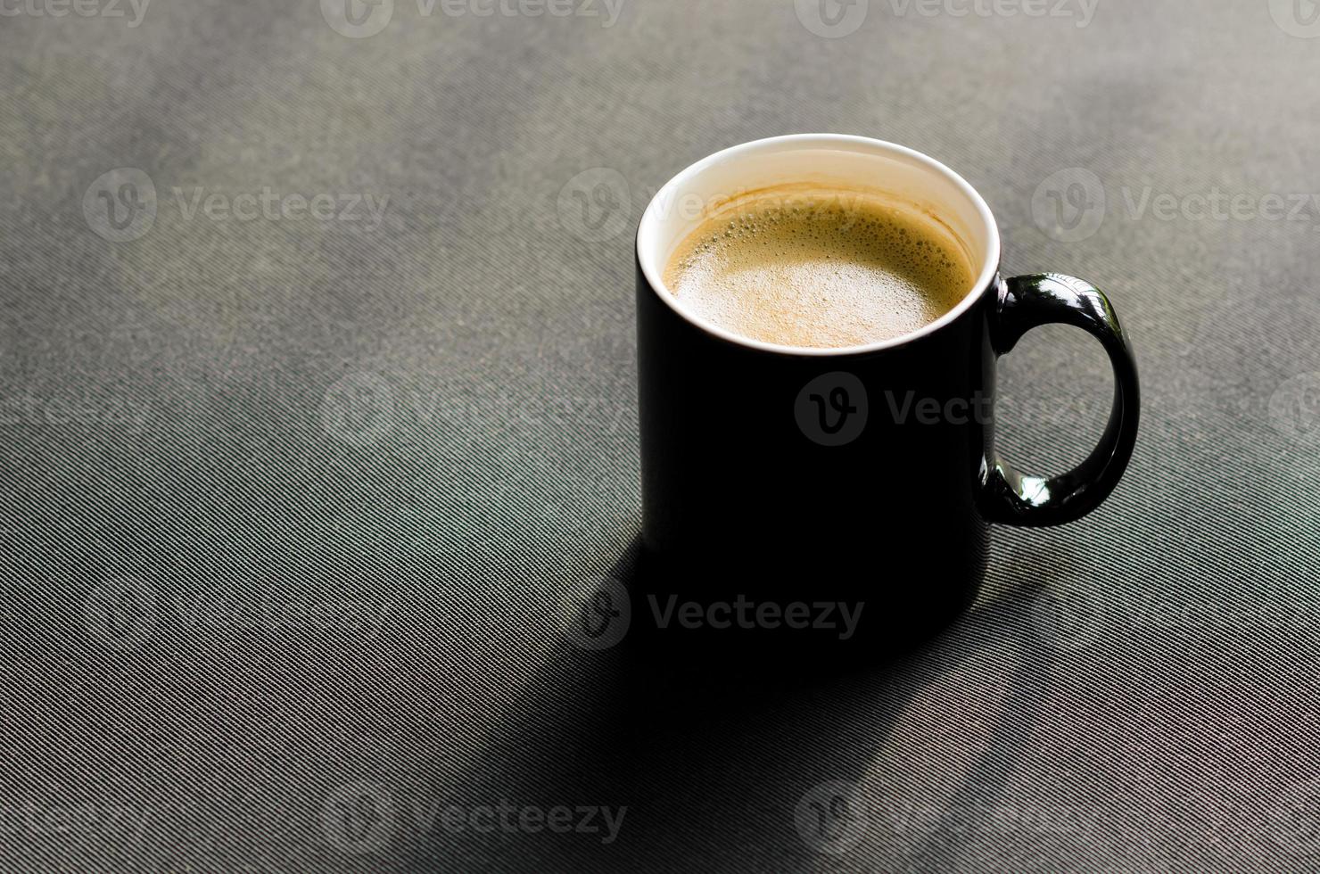 une tasse noire de café chaud posée sur un canapé de balcon avec ombre photo