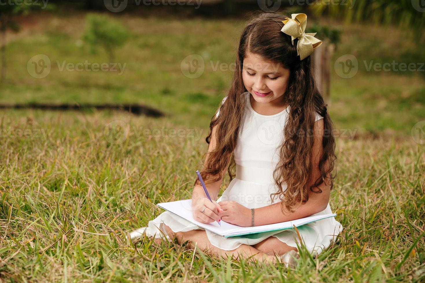 petite fille avec un livre dans le jardin. enfant lit un livre à la ferme. étudier à l'extérieur en été. campagne. brésilienne. photo