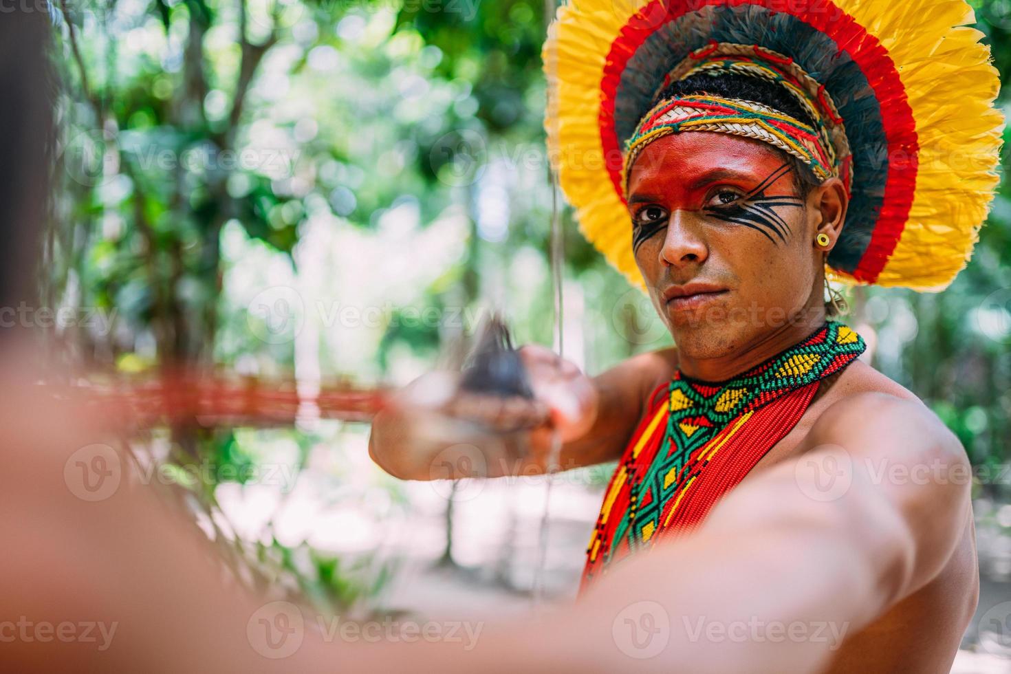 indien de la tribu pataxo utilisant un arc et des flèches. indien brésilien avec coiffe de plumes et collier photo