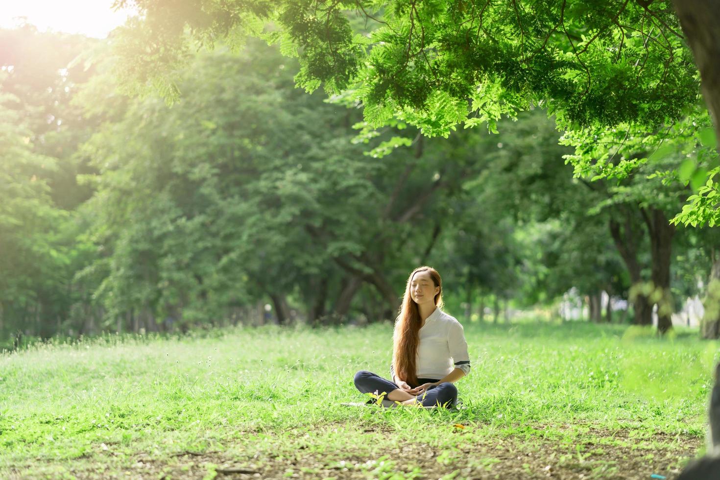 femme asiatique vêtue d'une robe blanche méditation dans le parc photo