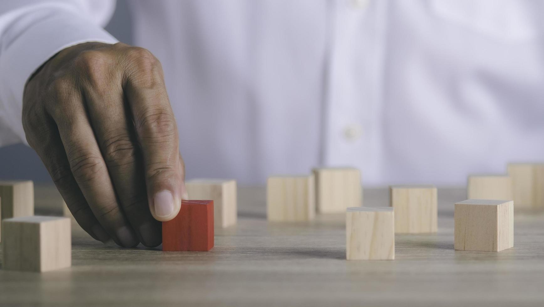 le jeune homme d'affaires se dirige vers le bloc de bois rouge posé sur la table, photo