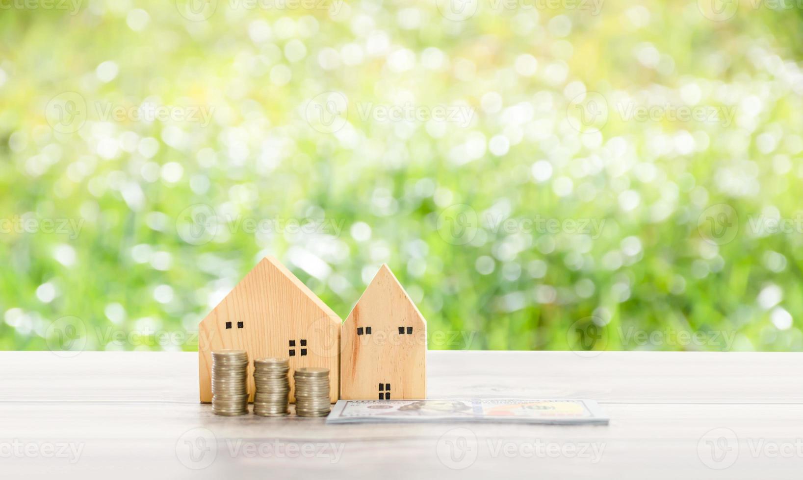 maison en bois simulée sur l'herbe de fond floue dans le jardin avec un espace de copie en haut. le concept de budget immobilier, pile, argent, pièces de monnaie, dollars, bois, table. mise au point sélective. photo