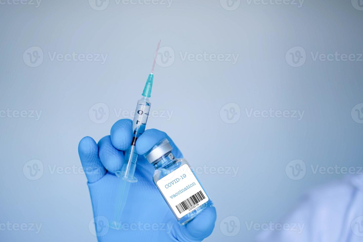 un homme tenant une seringue et une bouteille de vaccin le concept d'essais en laboratoire de vaccins un scientifique utilisant une seringue le médecin est sur le point de tester la vaccination contre le coronavirus. arrière-plan flou blanc. photo