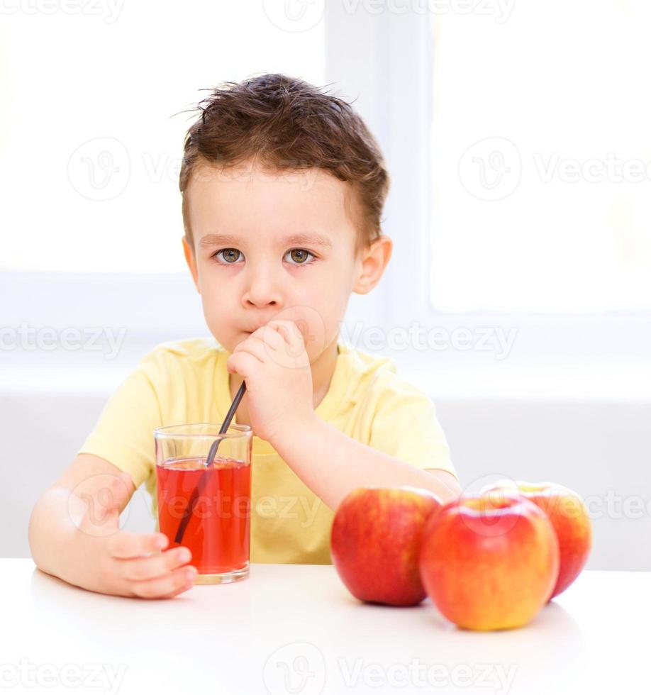 petit garçon avec un verre de jus de pomme photo