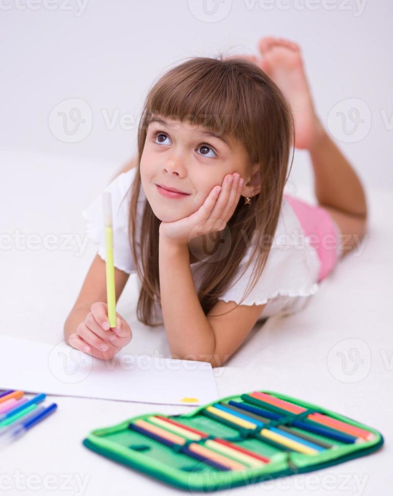 petite fille dessine à l'aide de crayons photo