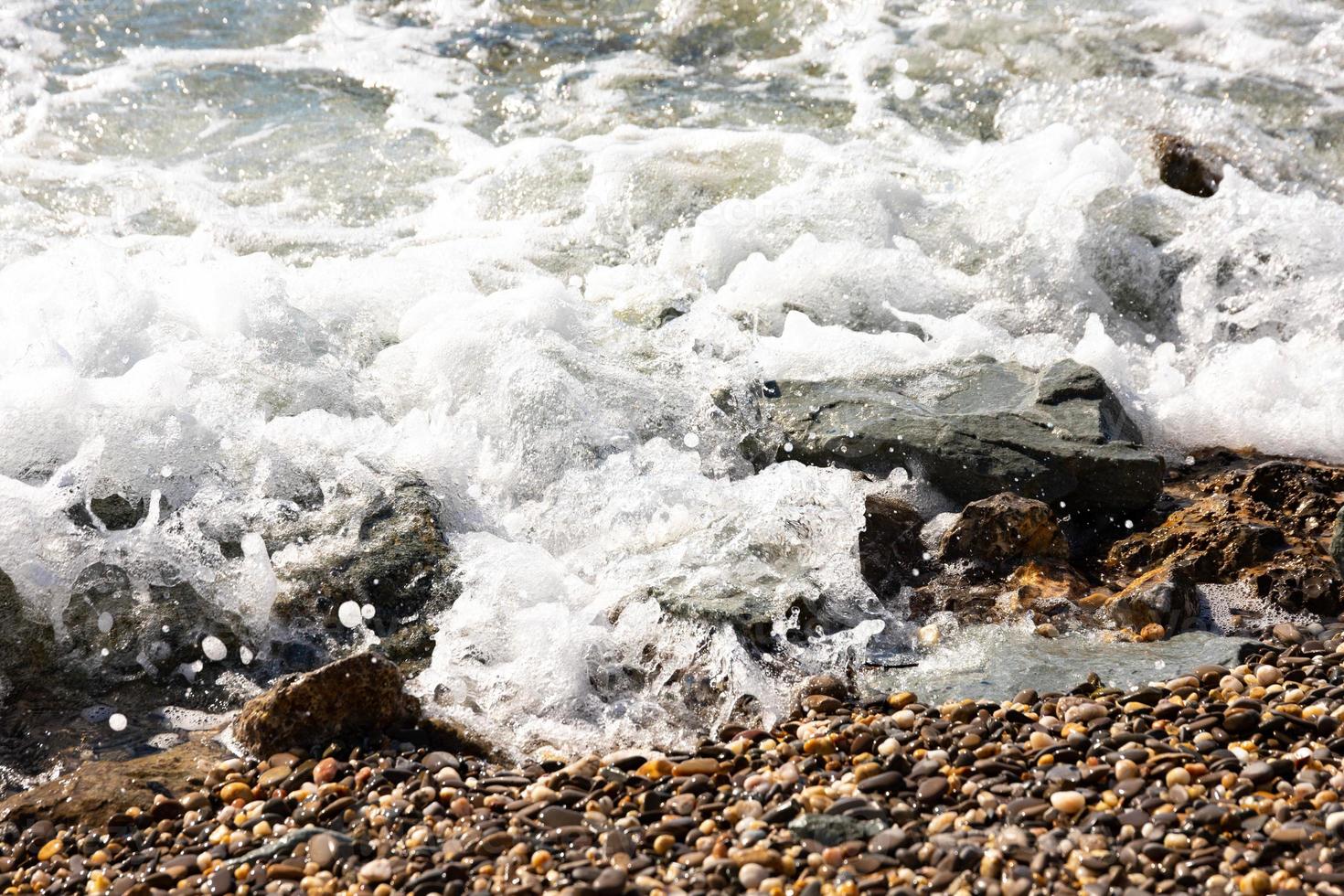 belle image de fond de galets sur la plage avec vagues et mer. photo