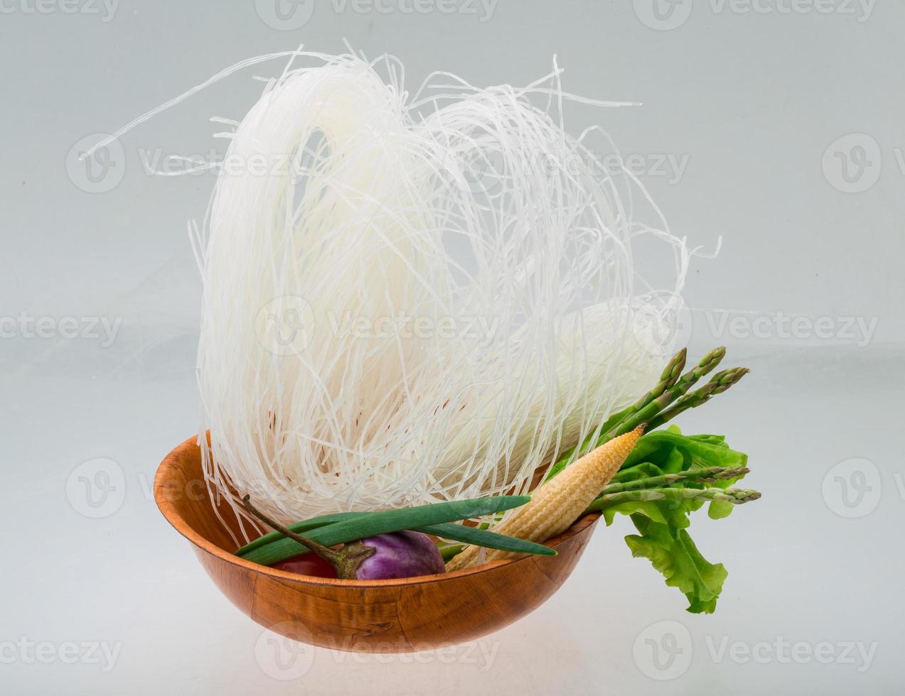 nouilles de riz crues dans un bol sur fond blanc photo