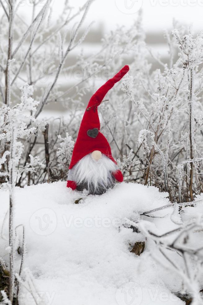 un petit jouet assis dans la neige en vêtements rouges photo
