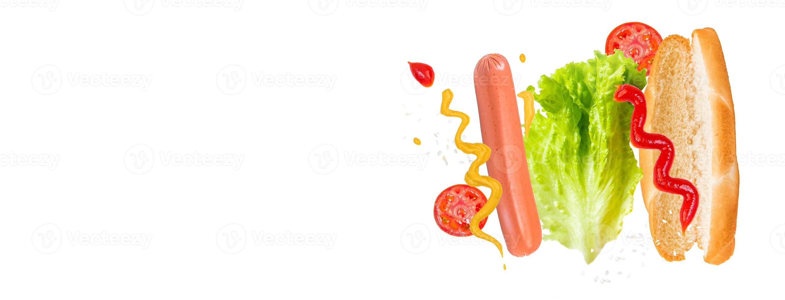 ingrédients volants pour un délicieux hot-dog sur fond blanc. saucisse en lévitation, tomates et laitue. photo