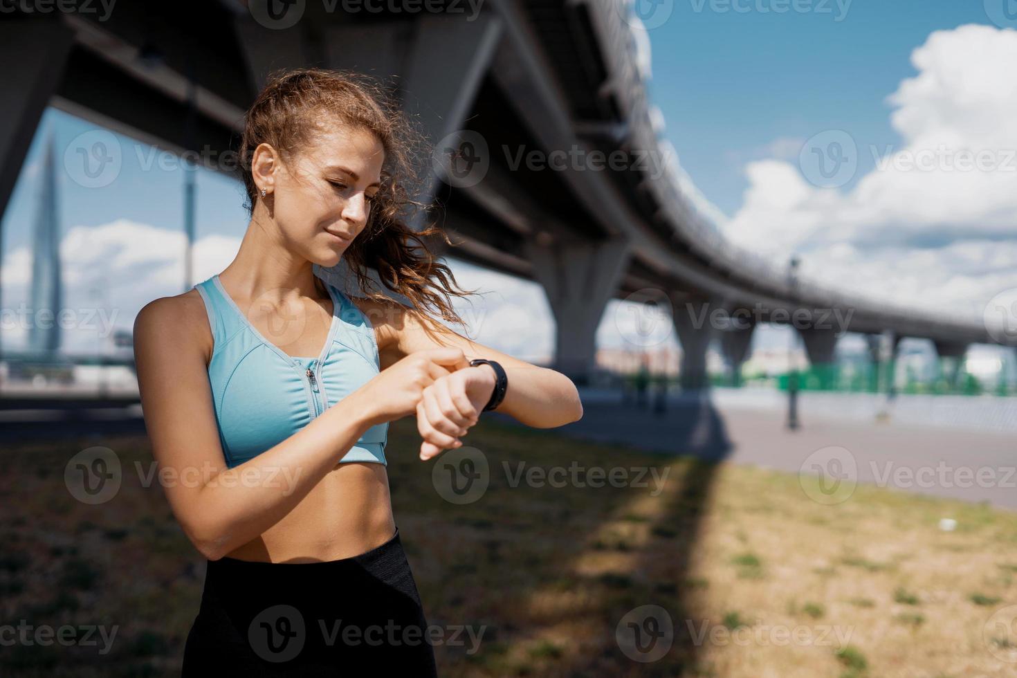 la montre intelligente vérifie les calories et le cardio. entraîneur de fitness brune athlétique. silhouette mince et vêtements confortables. concept de mode de vie sain. photo