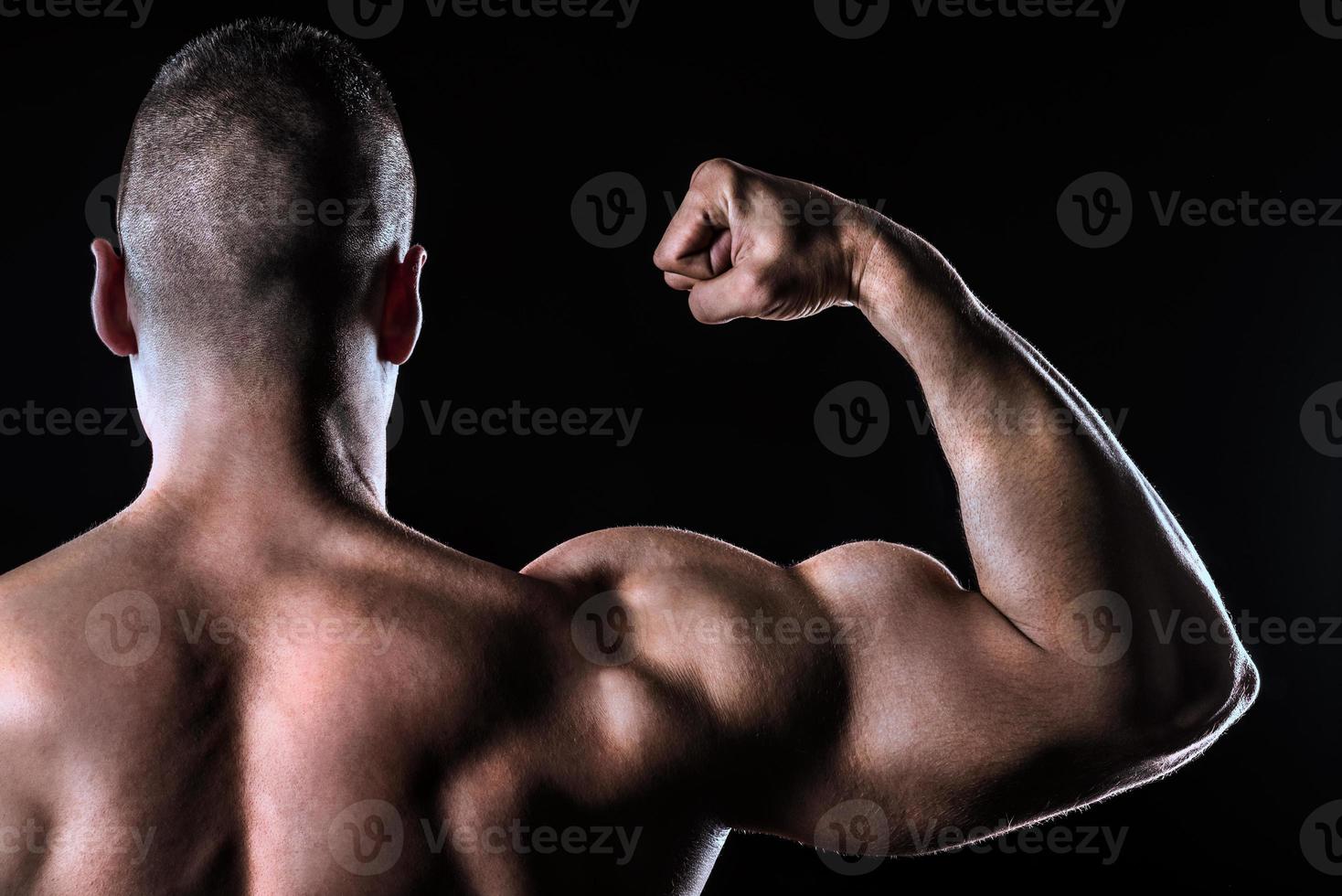 athlète fort montrant vue arrière biceps isolé sur noir photo
