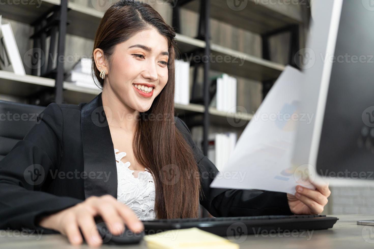 portrait d'une jolie femme d'affaires utilisant un ordinateur sur le lieu de travail dans un bureau. femme d'affaires positive souriante regardant sur papier. photo