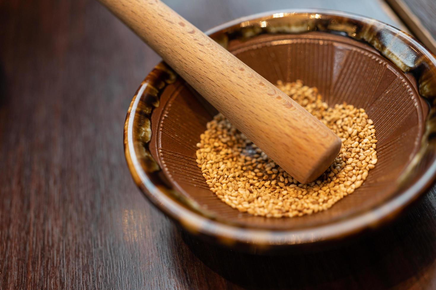 bol de broyage de sésame japonais et bâton en bois. bol en bois au sésame blanc pour broyer sur une table en bois. petit bâton pour escalope de porc japonaise photo